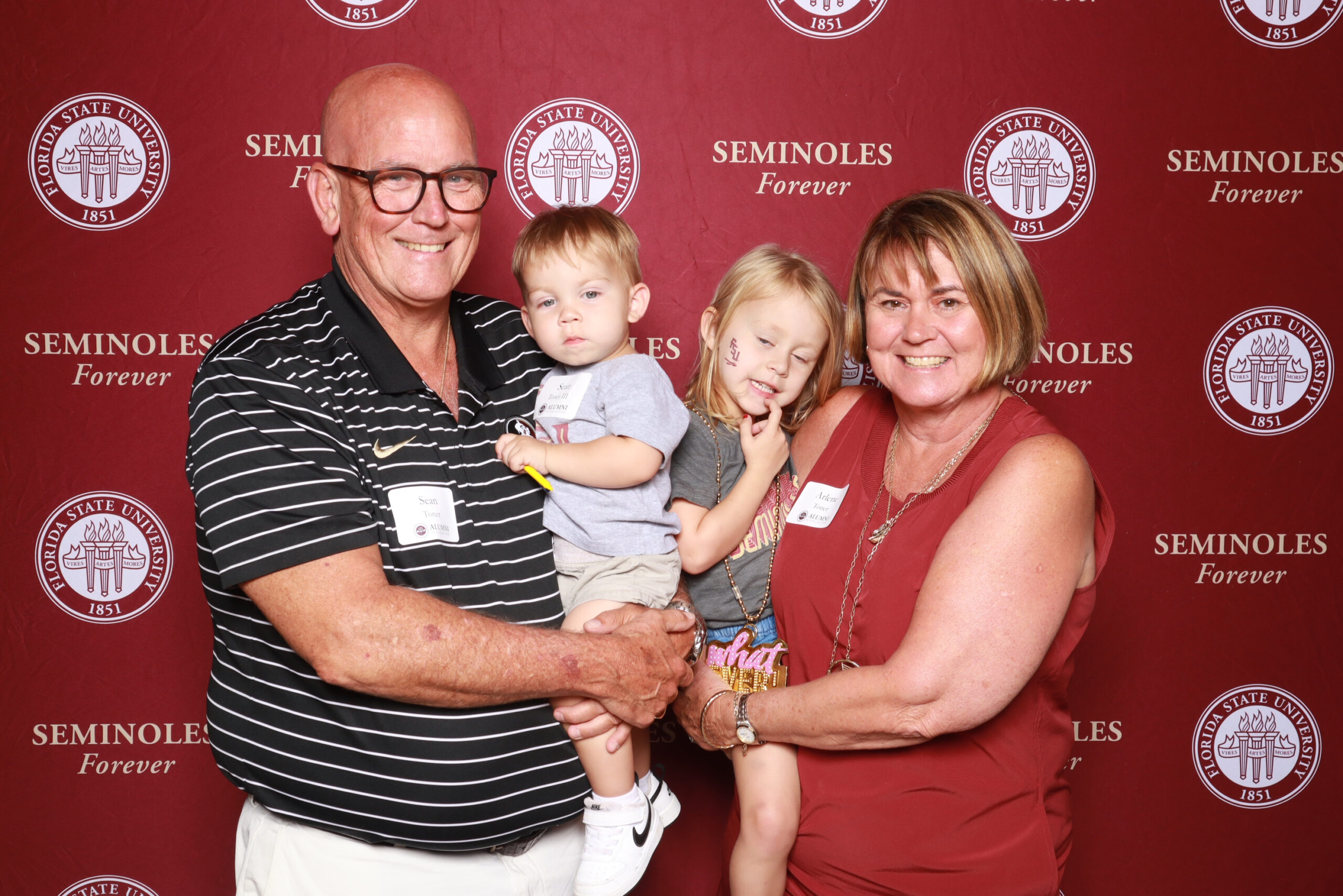 FSU alumni posing in front of a garnet and gold-themed photo booth in Orlando