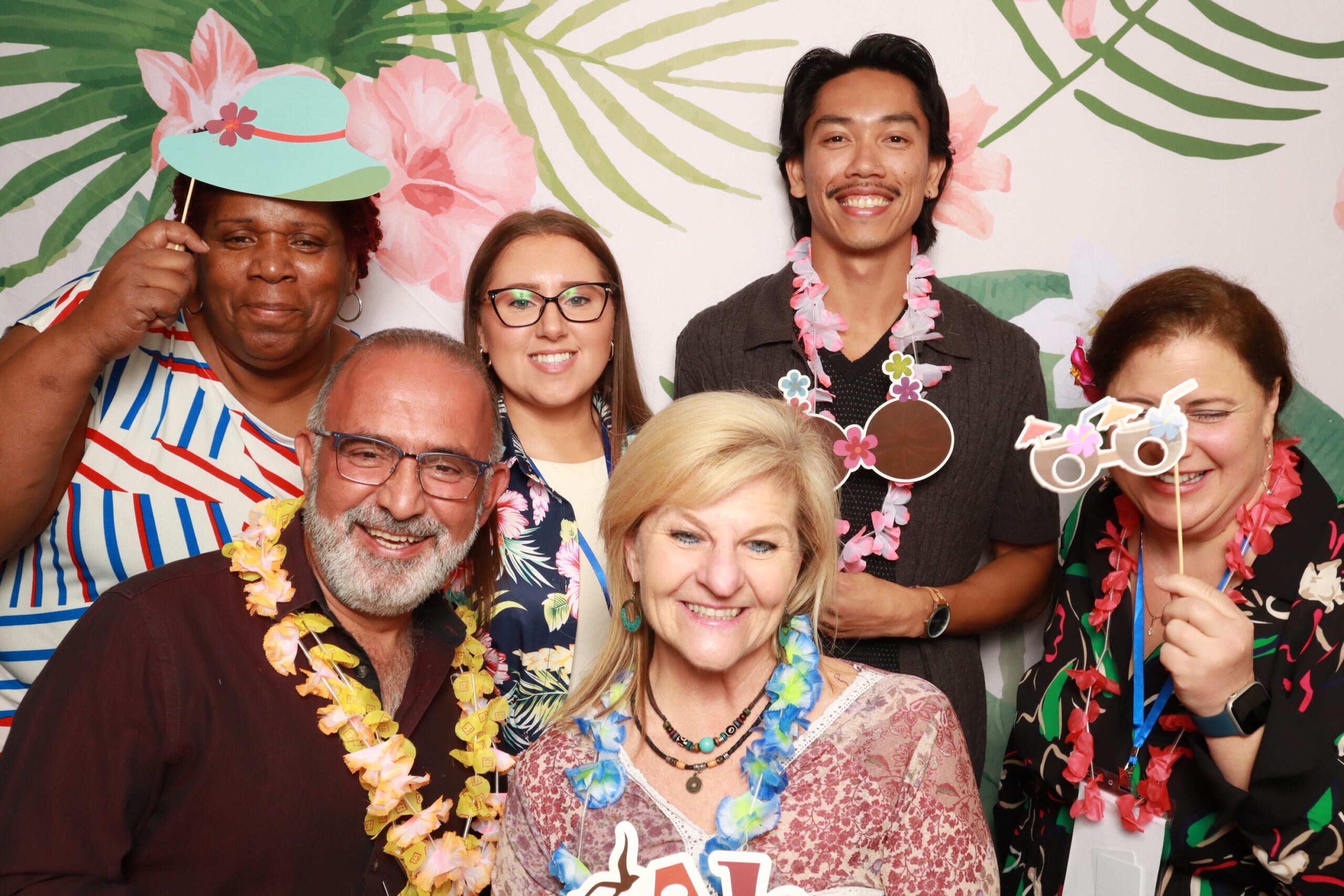 Group of attendees in tropical leis posing at FORWARD Conference Luau Night photo booth Orlando