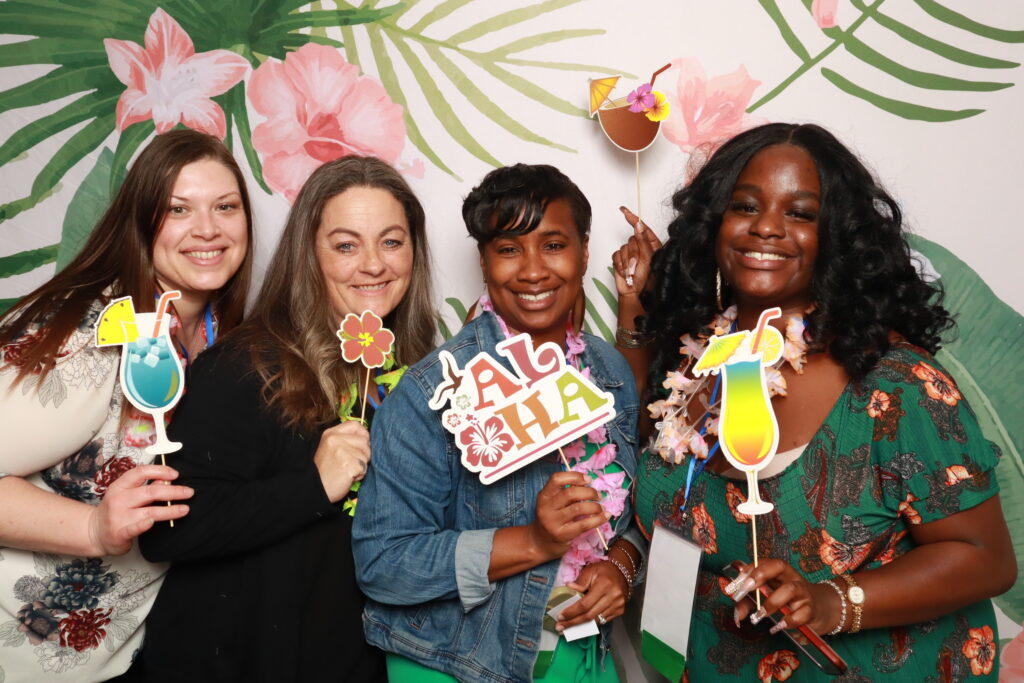 Attendees holding tropical cocktail props at Luau Night photo booth at FORWARD Conference Orlando