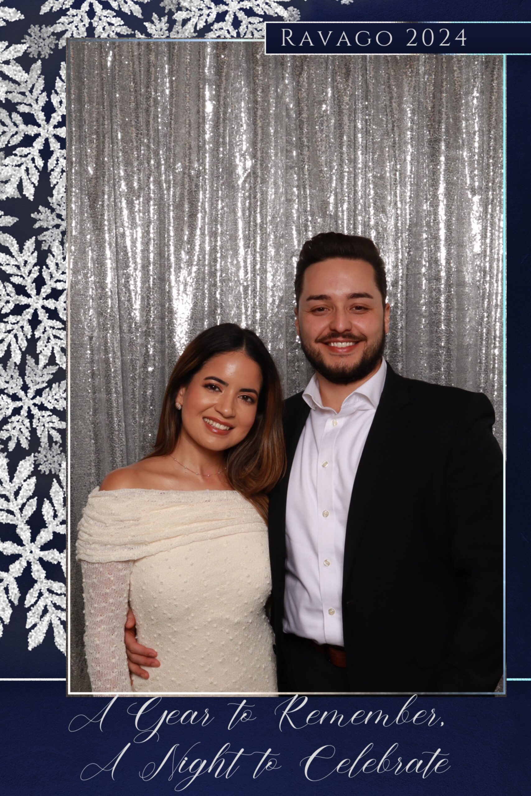 Christmas Photo Booth: Couple dressed in formal attire posing in front of a silver sequin backdrop with a Ravago 2024 holiday frame.