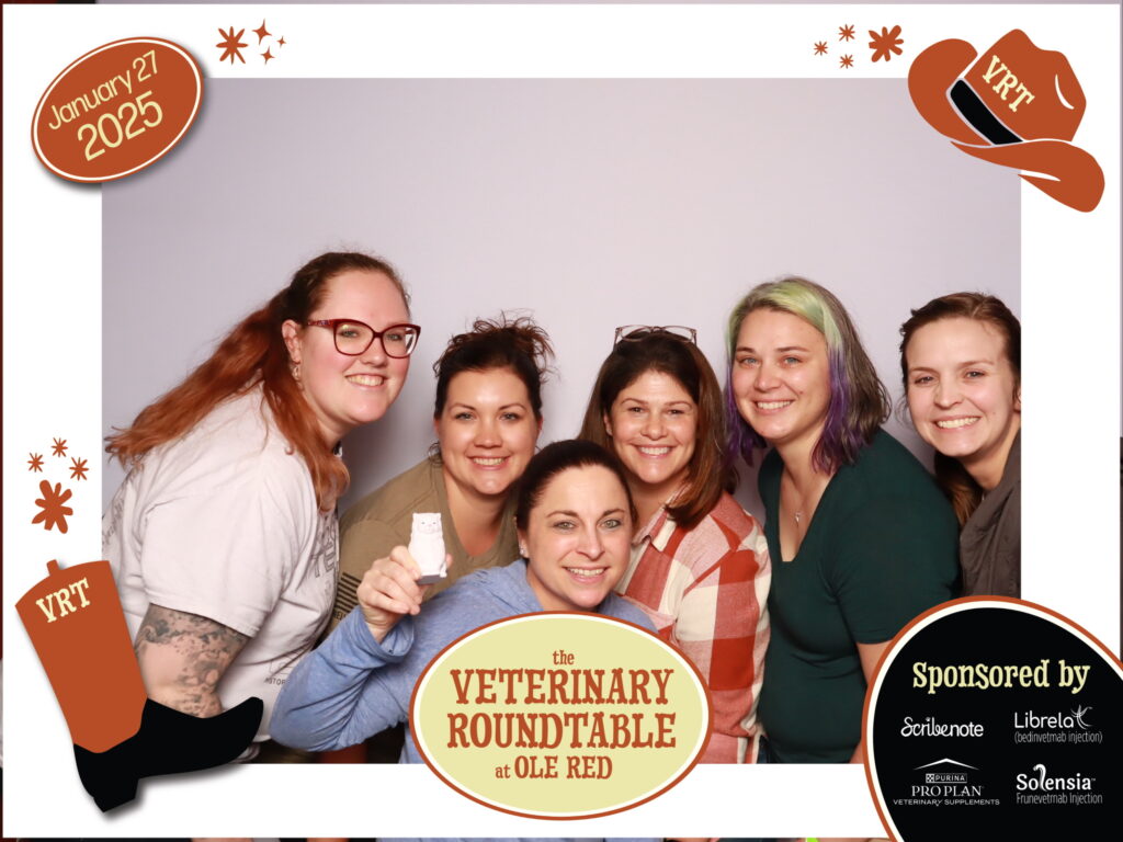 Two attendees hugging and smiling in a branded photo booth frame at Ole Red during the Veterinary Roundtable Live Podcast Show