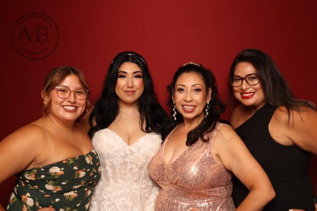 Group of wedding guests smiling and holding drinks in front of red photo booth backdrop at Lake Mary wedding